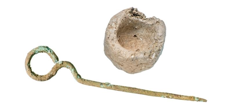 A metal pin with a circular head and a small pot