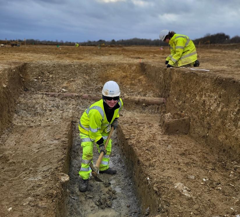 Two archaeologists excavating a ditch