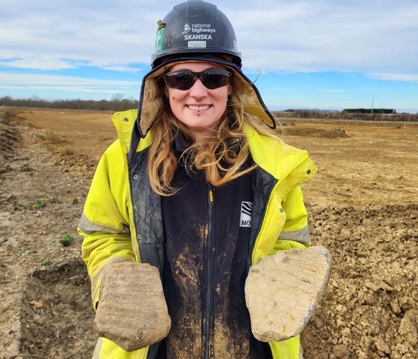 An archaeologist holding two pieces of millstone