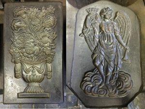 Two metal sheets one with an irn with flowers and one of an angel